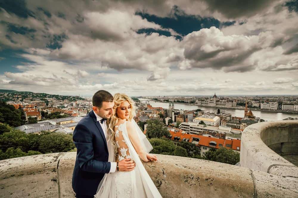 Luxury wedding couple overlooking Budapest cityscape with historic architecture and Danube River.