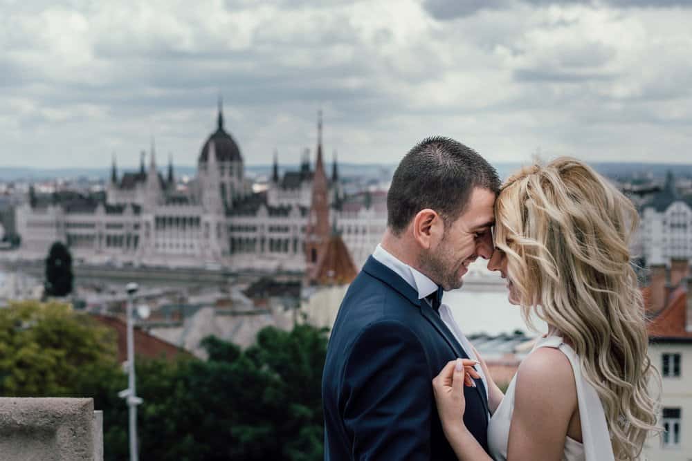 Elegant couple on rooftop overlooking historic cityscape, perfect for luxury wedding photos.