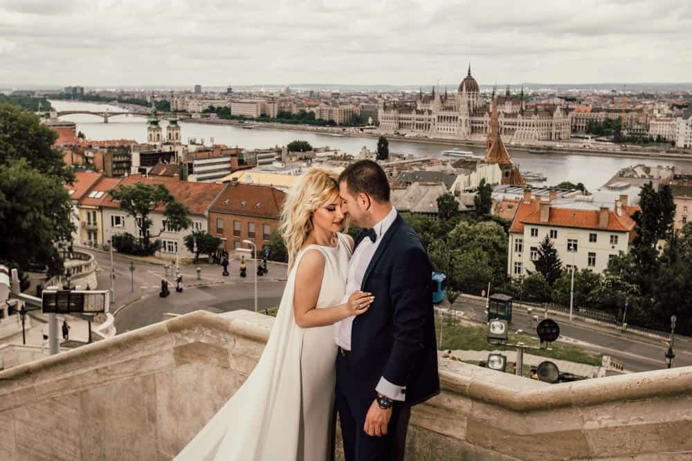 Elegant wedding couple overlooking Budapest skyline at high-end venue, showcasing luxury wedding photography.