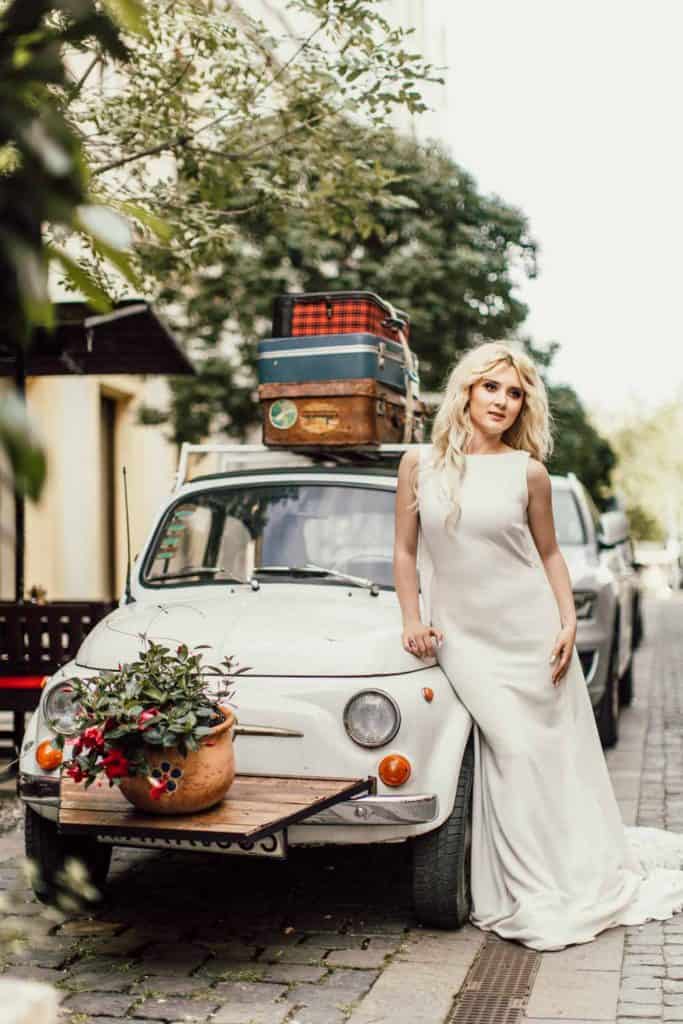 Vintage wedding car with luggage on roof and flower bouquet, outdoor luxury wedding scene.