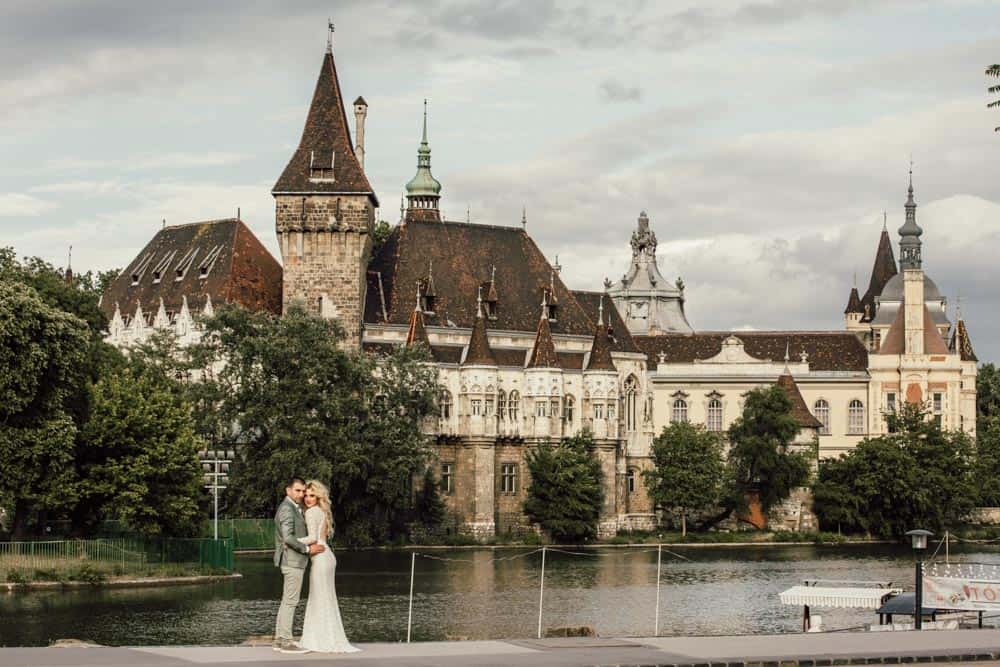 Elegant wedding couple in front of a historic castle on the river.
