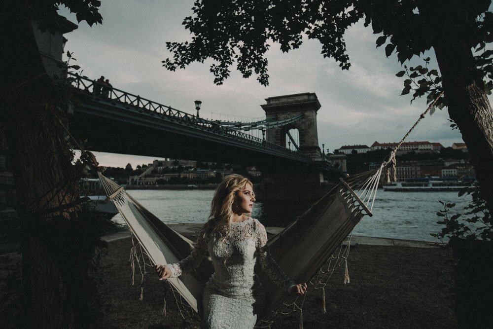 Bridal bride in elegant wedding dress relaxing by the river in outdoor luxury wedding setting.
