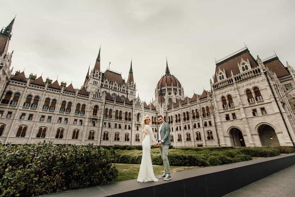 Luxury wedding couple outside a grand historic castle at a high-end venue.