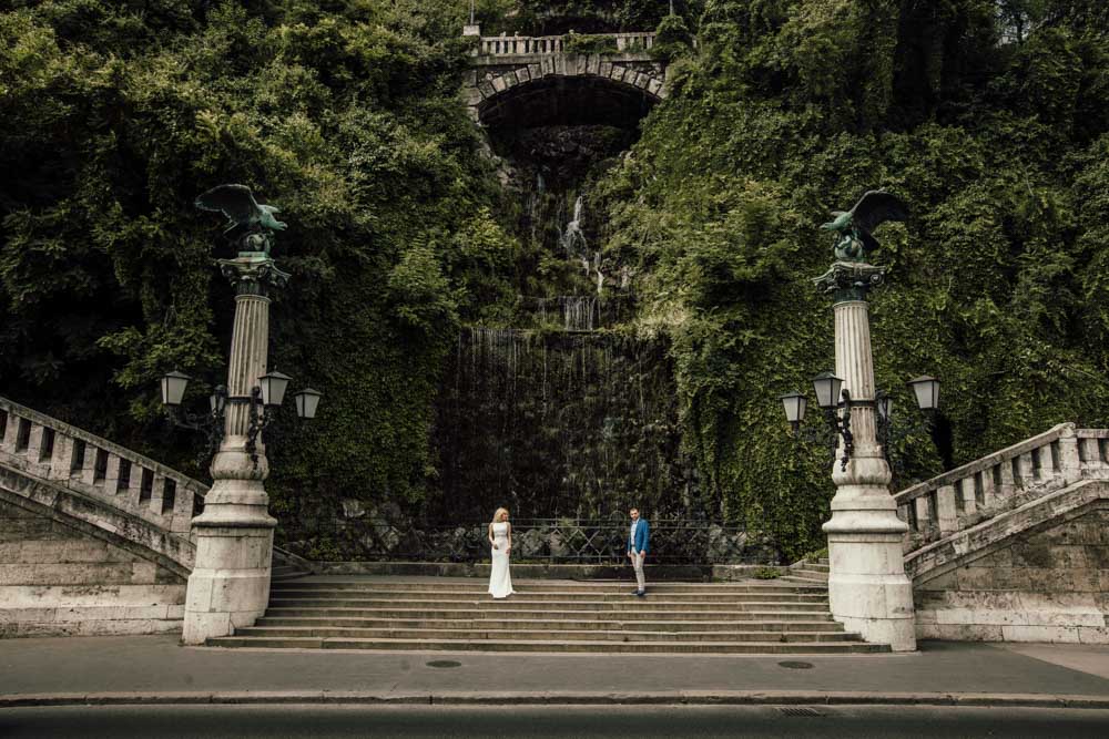 Luxury wedding at historic outdoor venue with lush greenery and grand staircase.