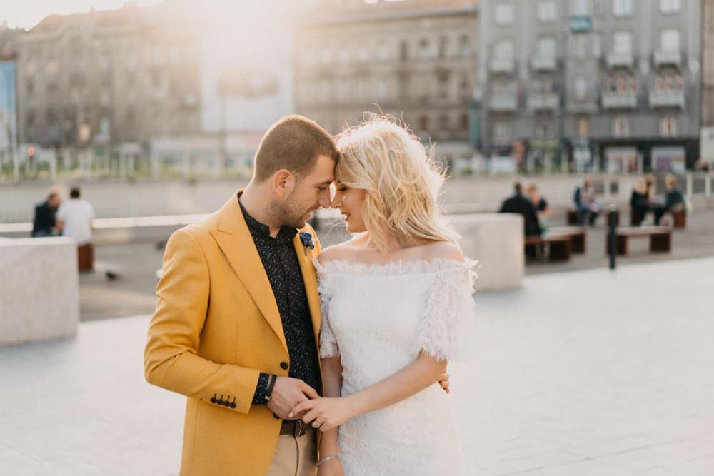 Elegant couple sharing tender moment outdoors at luxury wedding venue in the city.