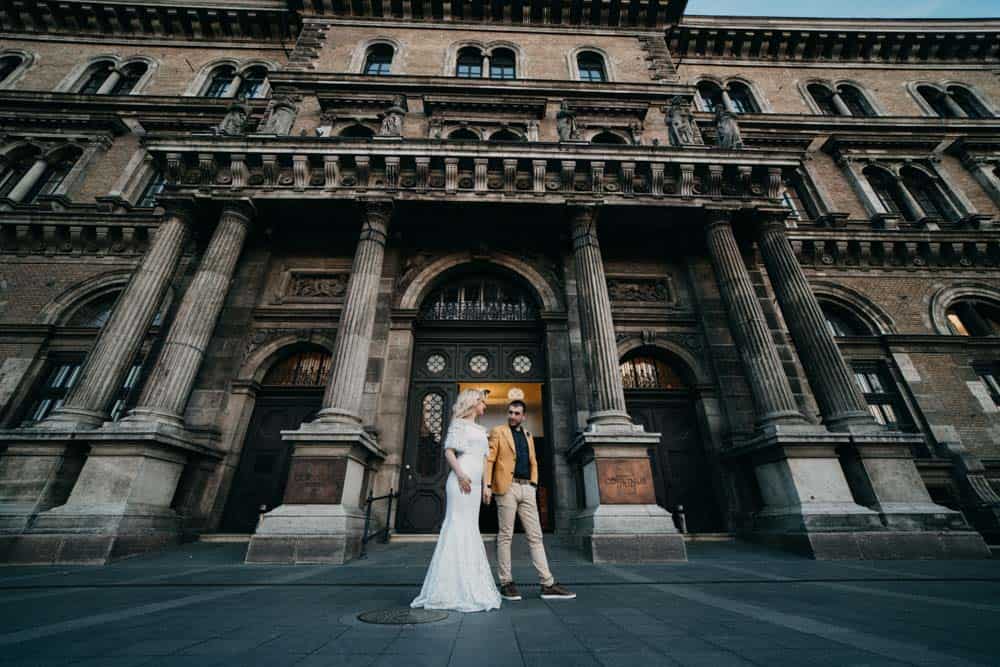 Luxury wedding couple in front of historic high-end venue building, elegant wedding photography.