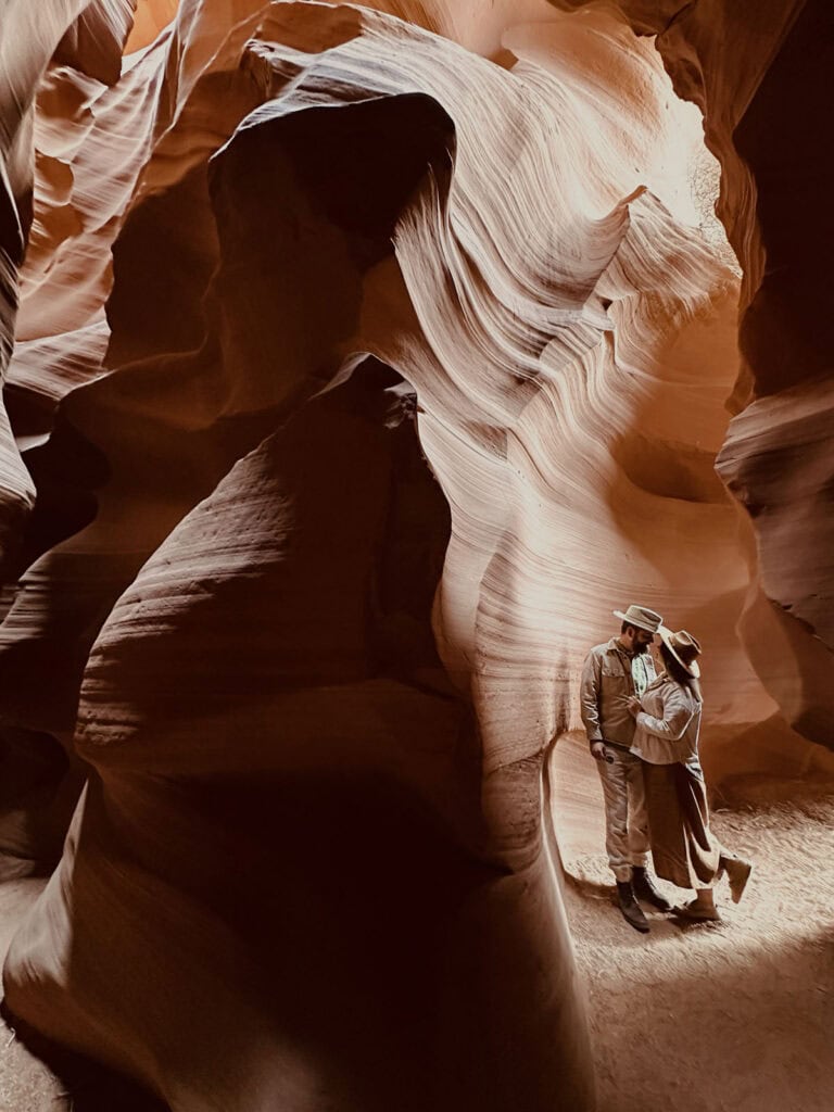 Discover a romantic moment between a couple in a stunning slot canyon with smooth, flowing sandstone walls illuminated by natural light, showcasing the beauty of luxury adventure wedding destinations.