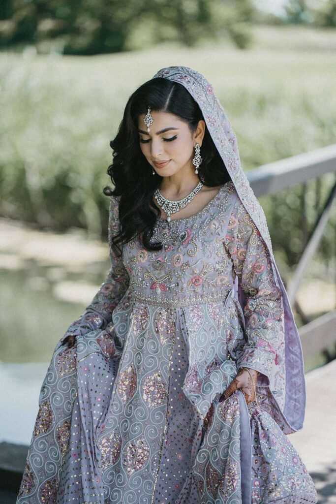 Elegant bride in traditional intricate wedding attire with silver jewelry, outdoors in a luxurious wedding setting.