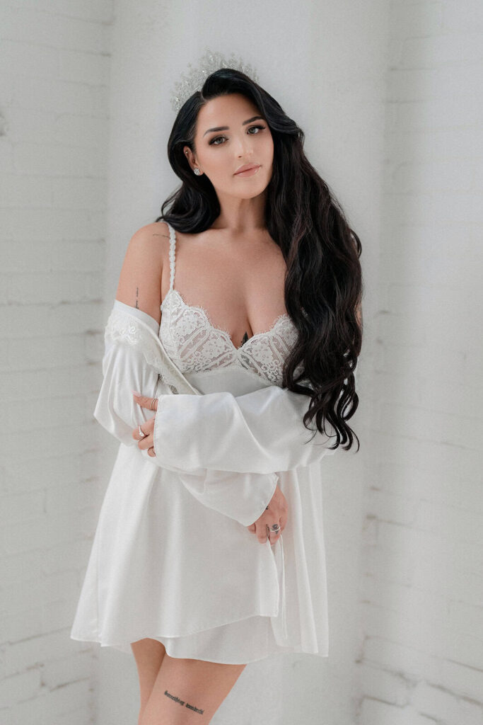 Elegant bride with long dark hair and lace nightwear in a modern luxury wedding setting.