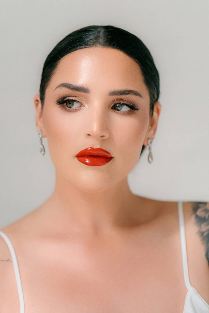 Elegant bride with flawless makeup, sleek dark hair, and sparkling earrings, showcasing high-end wedding beauty styles.