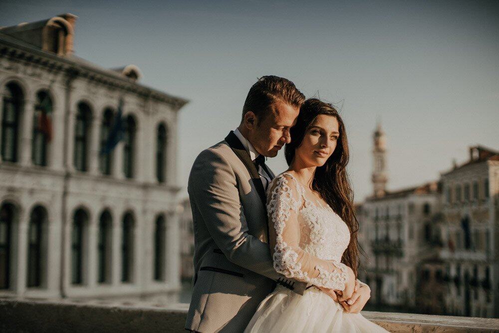 Elegant wedding couple on a balcony overlooking historic architecture at a luxury high-end venue.