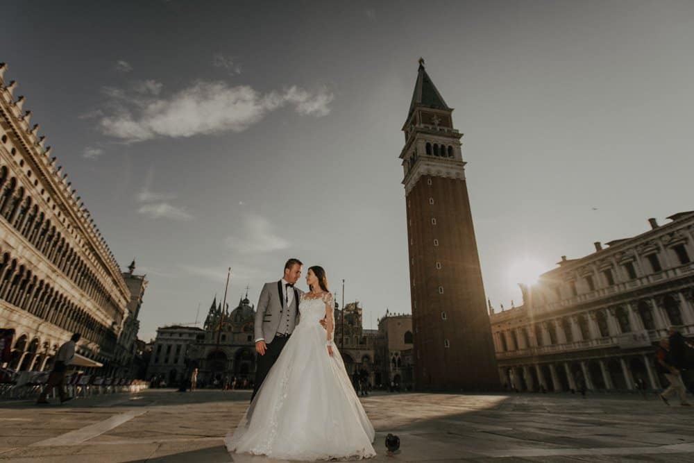 Elegant wedding couple in Venice square during sunset, showcasing luxury wedding style and high-end venue.