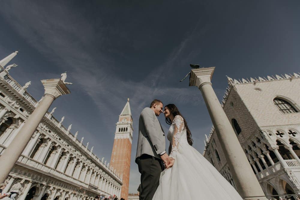 Elegant bride and groom in Venice, Italy, with historic architecture and iconic bell tower in background.