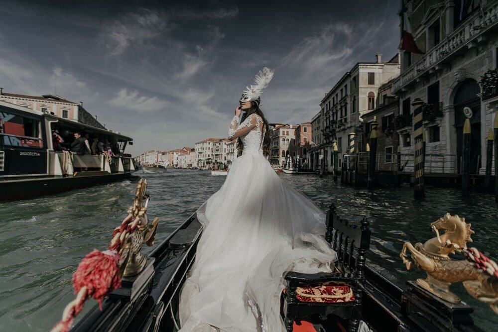 Elegant bride in a luxurious white gown on a gondola in Venice, showcasing high-end wedding destinations.