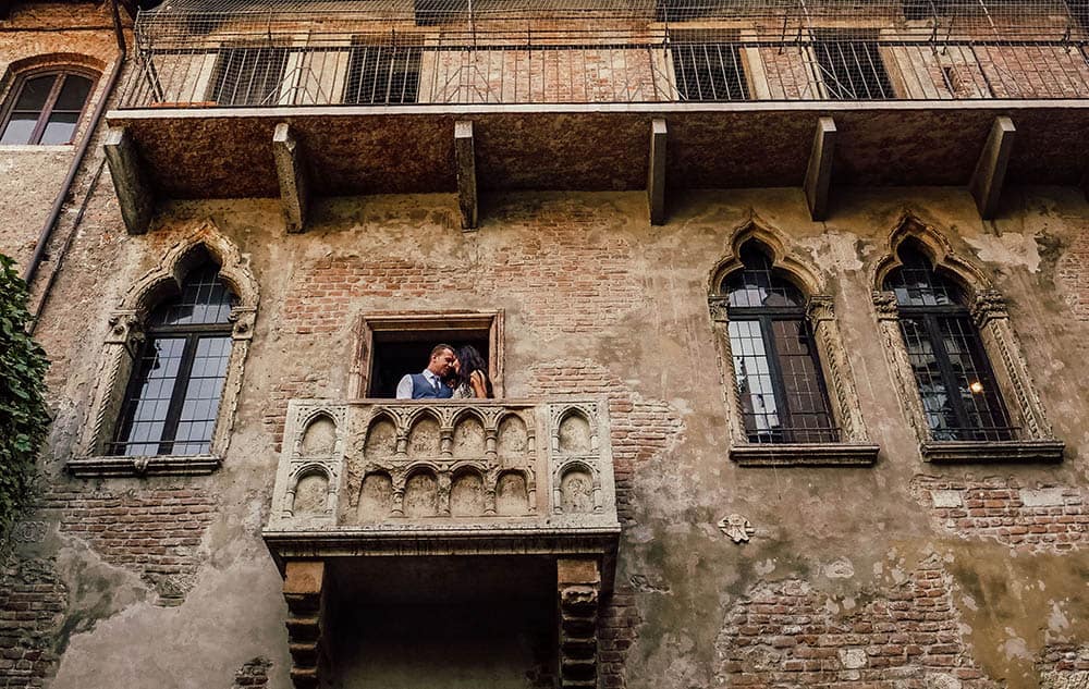 Elegant couple sharing a romantic moment on a historic Venetian balcony at a luxurious wedding venue.