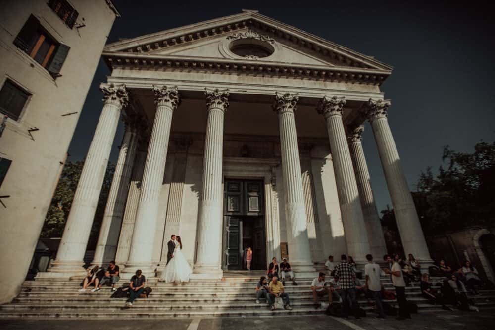 Luxury wedding ceremony at grand neoclassical building with tall columns and elegant architecture.