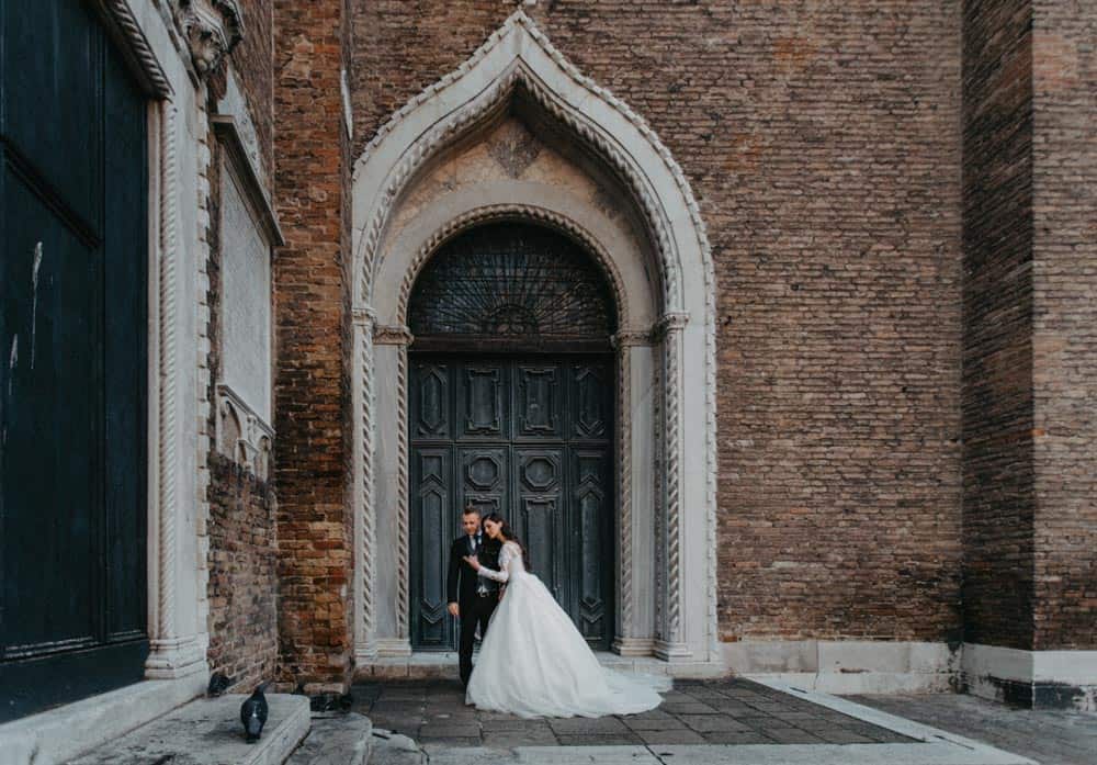 Elegant wedding couple standing in front of historic gothic door at a luxurious venue.