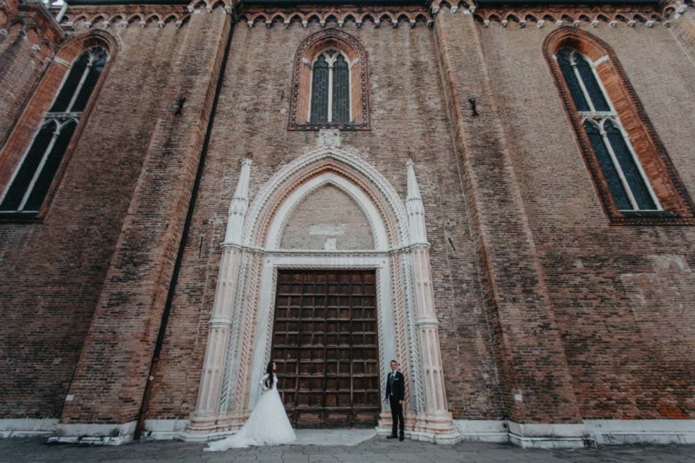 Elegant bride and groom in front of historic church for luxury wedding ceremony.