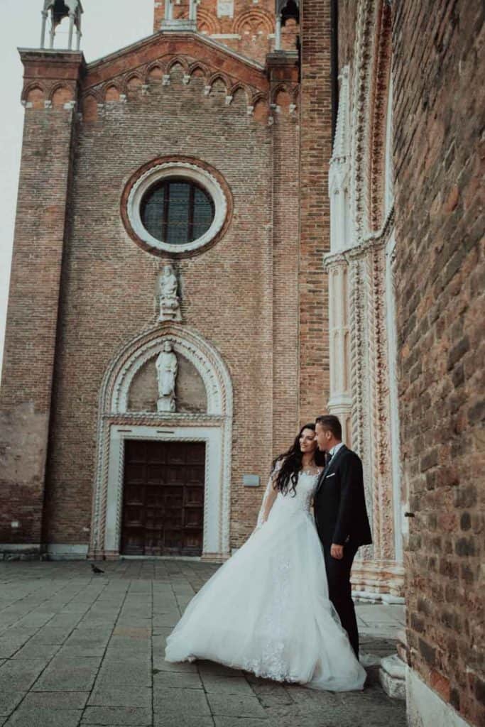 Elegant bride and groom in front of historic church on wedding day.