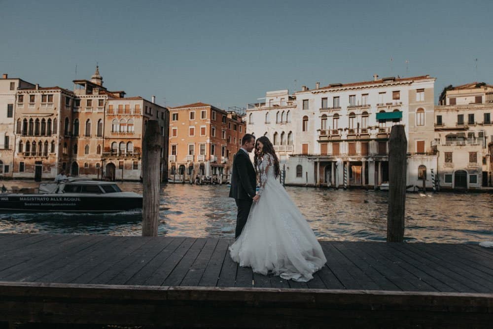 Elegant bride and groom sharing a romantic moment on a Venice canal dock, showcasing luxury wedding photography at high-end venues.