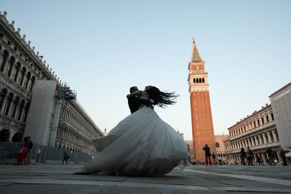 Elegant couple dancing in Venice Piazza, capturing a romantic moment against historic architecture.