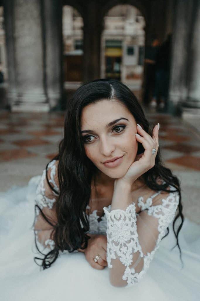 Elegant bride with dark hair and lace wedding gown at luxurious, high-end venue, showcasing sophisticated wedding fashion and attention to detail.