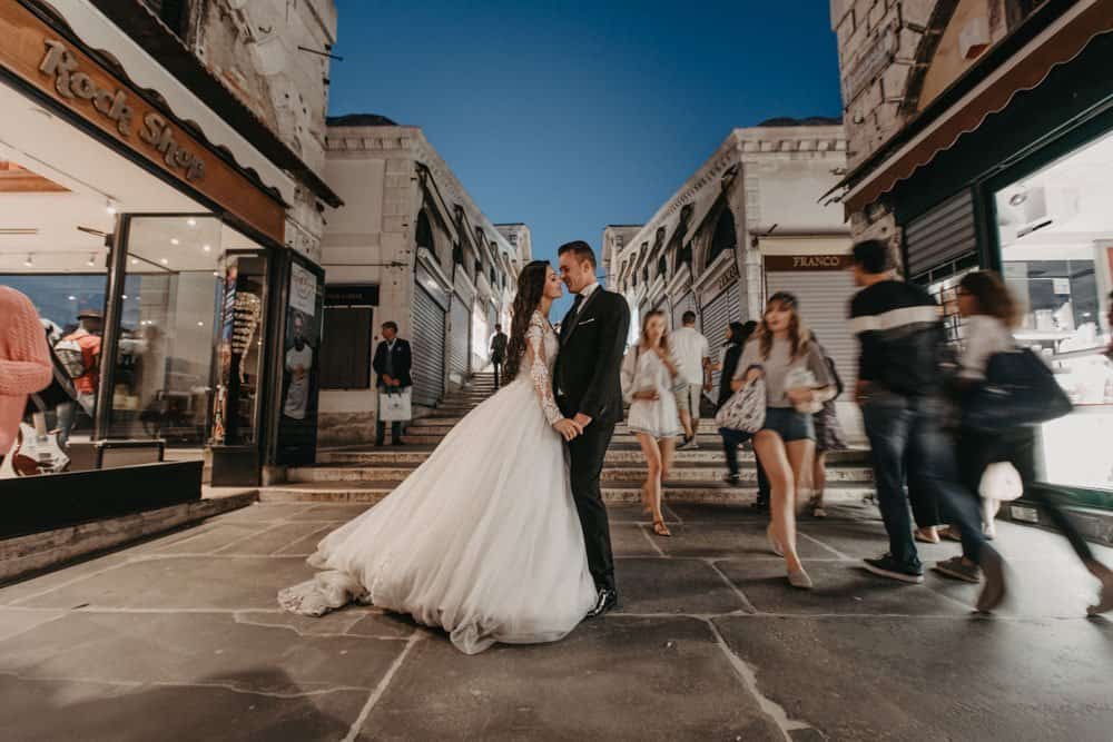 Elegant wedding couple embracing on a vibrant city street at dusk, showcasing luxury urban wedding photography.
