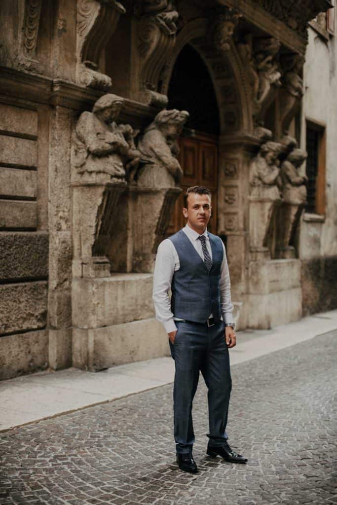 Elegant man in tailored suit standing in front of historic stone architecture, perfect for luxury wedding venues.