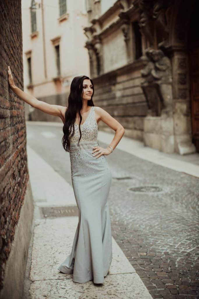 Elegant woman in a stunning silver wedding dress on a historic city street, showcasing luxury bridal fashion and high-end wedding attire.
