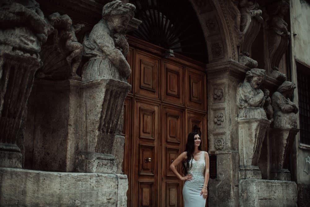 Elegant bride standing in front of historic, ornate architecture at a luxury wedding venue.