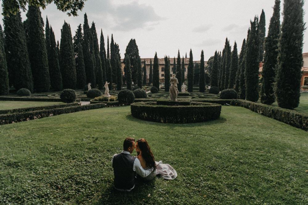 Lush garden with tall cypress trees and classical statues at a luxury wedding venue.