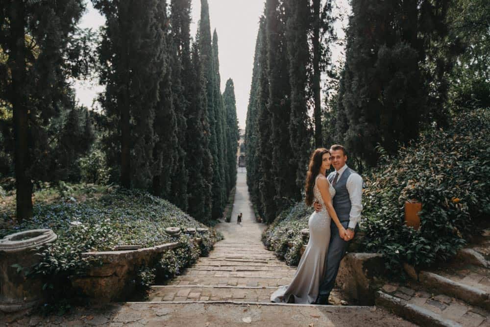 Luxurious wedding couple standing in a scenic garden pathway at high-end venue.