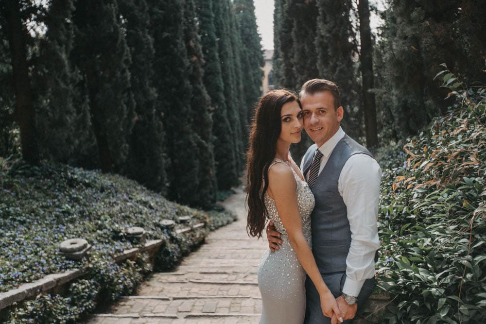 Elegant couple in wedding attire posing in a lush garden setting, perfect for luxury wedding photography.