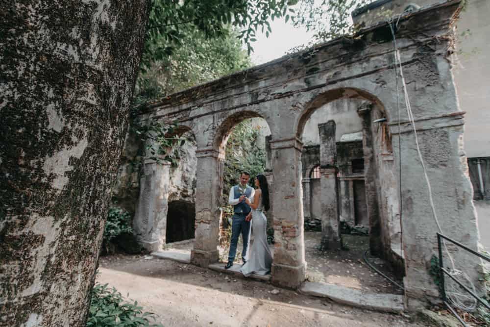 Rustic wedding couple exchanging vows at historic stone ruins in lush greenery.