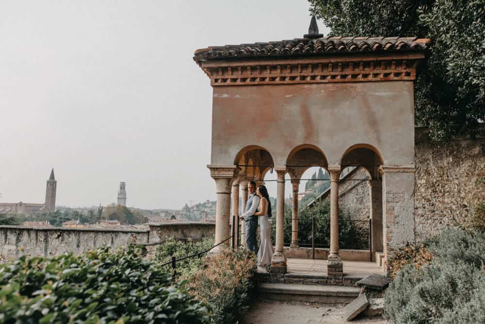 Elegant couple standing under a historic terrace at a luxury wedding venue in Italy.