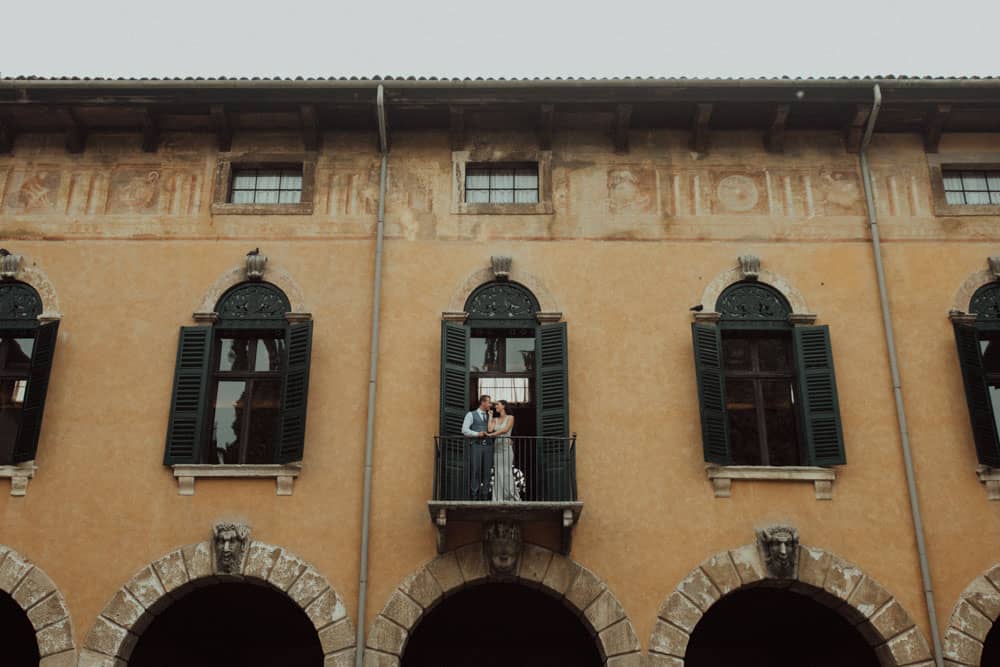 Luxury wedding couple on balcony of historic villa high-end venue romantic wedding photography.