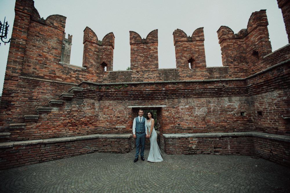 Elegant bride and groom posing in front of historic brick castle ruins, perfect for luxurious wedding photography at high-end venues.