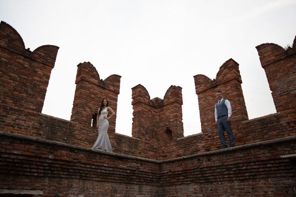 Elegant bride and groom standing on historic brick ruin at luxury wedding venue.