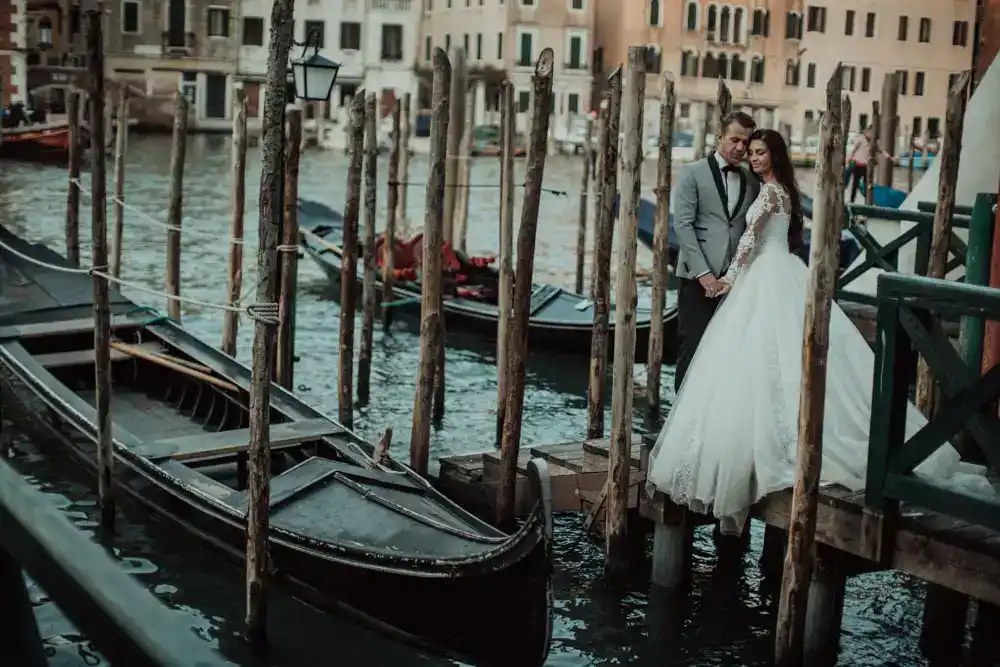 Venetian wedding couple on a romantic gondola dock in Venice, Italy, showcasing luxury wedding photography and high-end venue scenery.