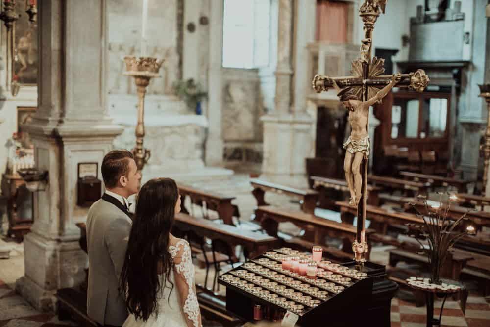 Elegant wedding ceremony inside a luxurious church with a beautifully adorned altar and religious statues.