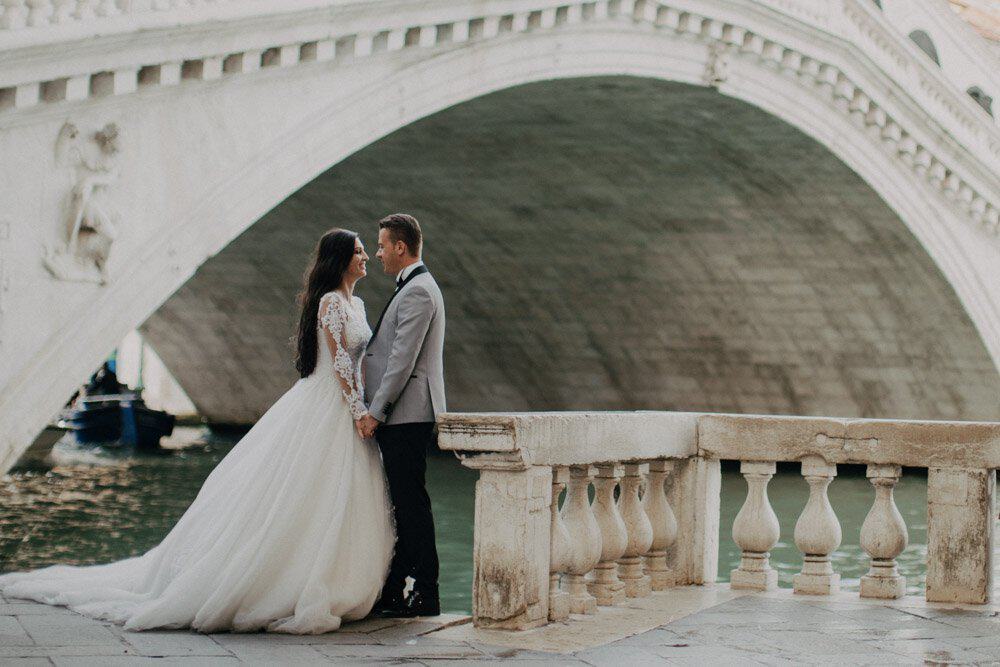 Elegant wedding couple holding hands on a bridge in Venice, Italy, perfect for luxury wedding photography.