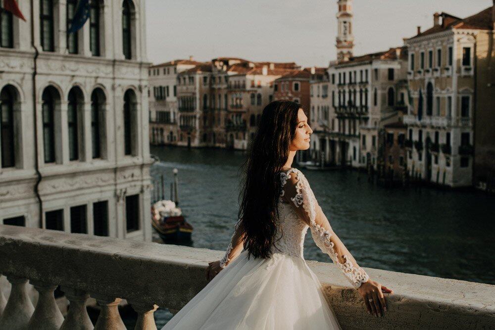 Venetian bride overlooking canals in an elegant wedding gown.