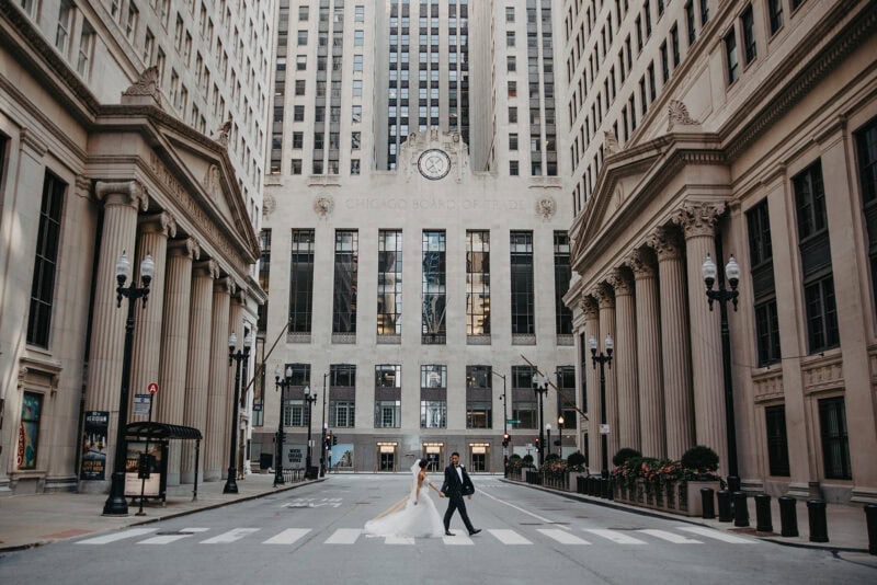 Elegant cityscape featuring a bride and groom crossing a historic downtown street with luxurious architecture.
