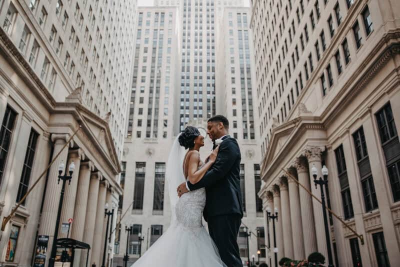 Elegant wedding couple embracing amidst stunning high-rise urban backdrop, showcasing luxury wedding photography.