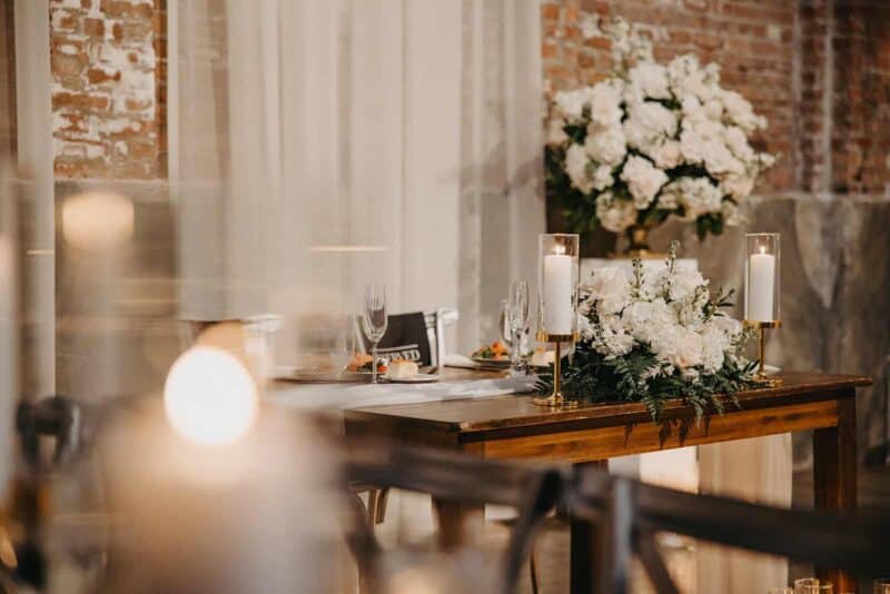 Elegant wedding table setup with luxurious floral arrangements and candle decor at high-end venue in an urban loft.