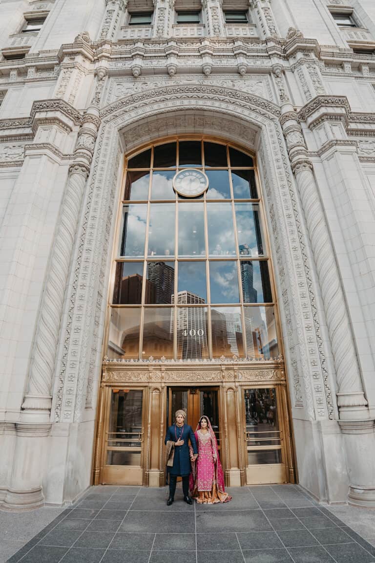 Stunning view of the ornate facade with two guests in traditional attire standing in front of the grand entrance.