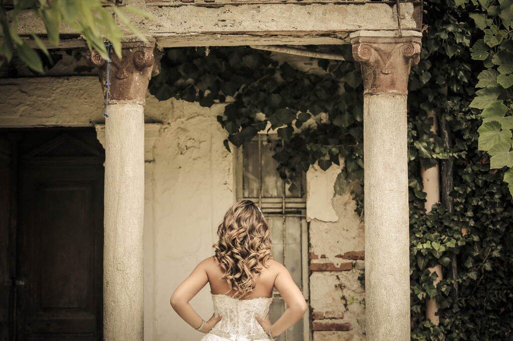 Elegant bridal portrait with lush greenery and rustic architecture, perfect for luxury wedding venues.