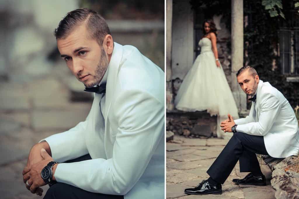 Elegant groom in white tuxedo with black bow tie, urban wedding setting.