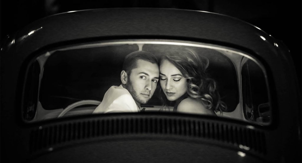 Vintage car interior with a romantic couple, black and white, high-end wedding photography.