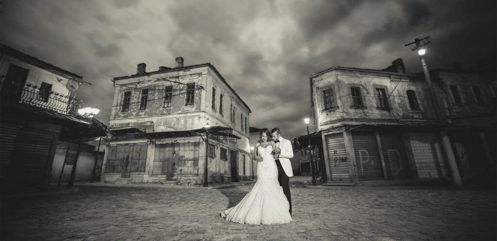 Sunset wedding couple in elegant attire at historic building backdrop, luxury wedding photography, romantic atmosphere, high-end venue, stylish event planning.